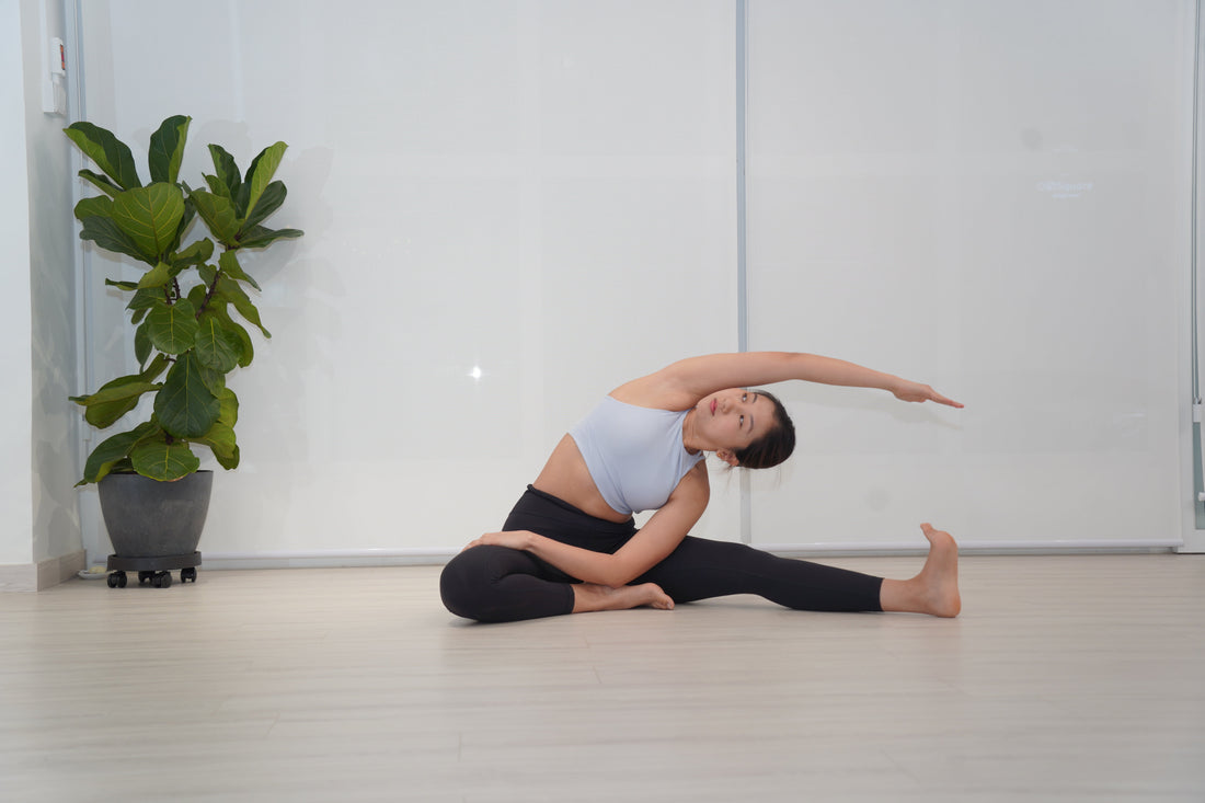 A yogini in a seated wide-legged pose with an extended side bend to the right.